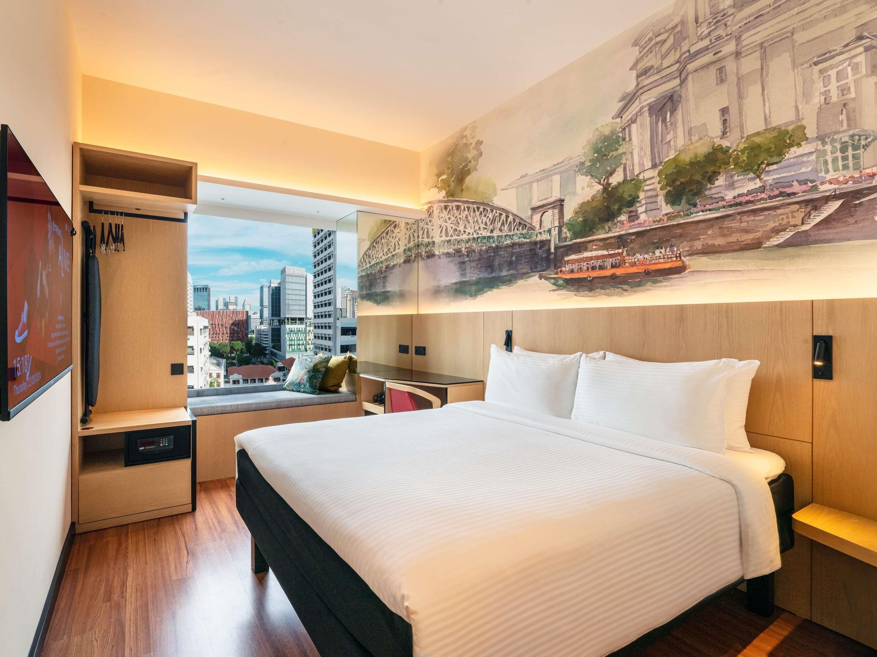 Une chambre d’hôtel comprenant un lit, un coin salon avec vue, une armoire et une fresque murale.