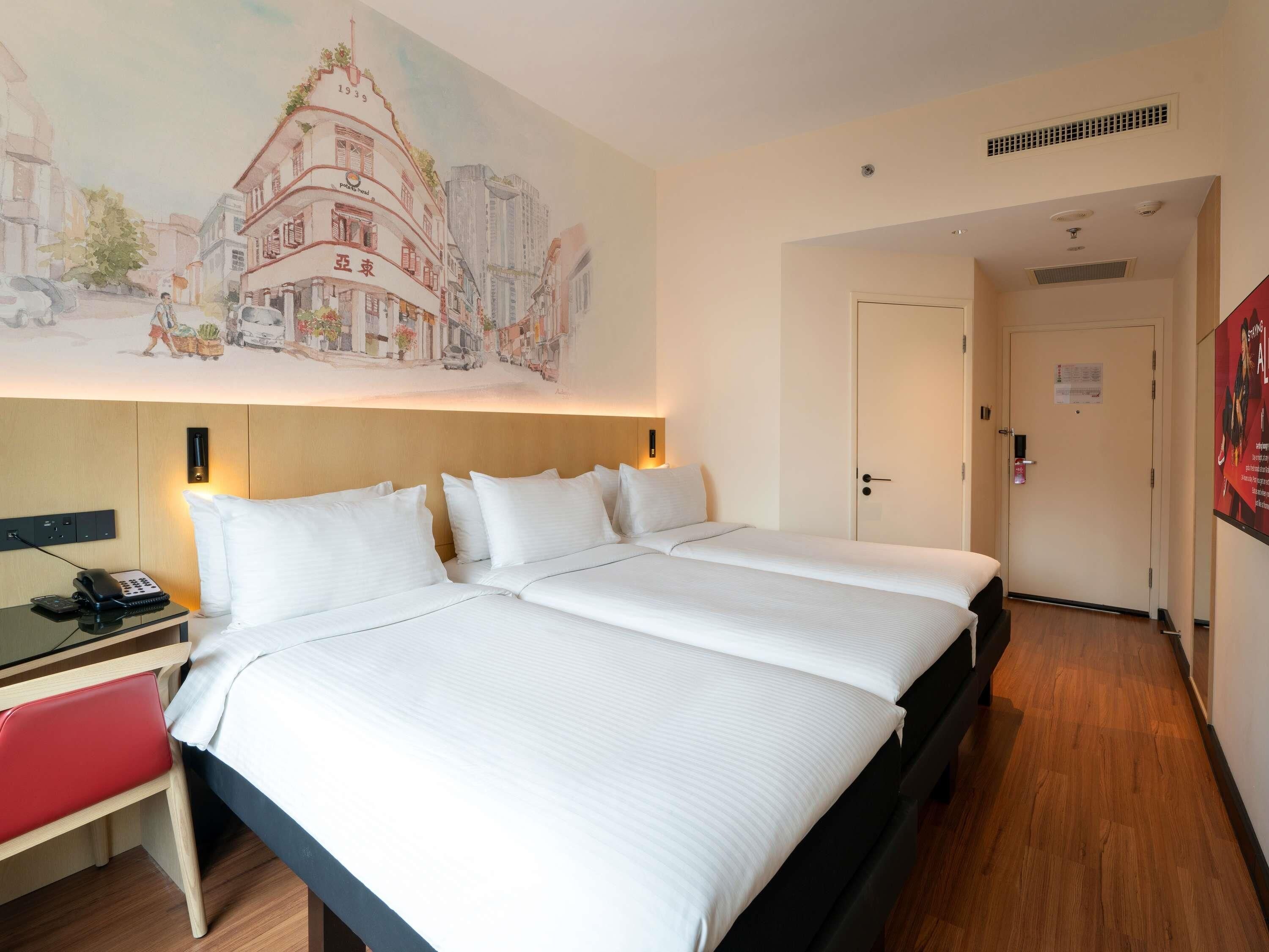A hotel room with a large bed, bedside tables, a desk, and a painting on the wall.
