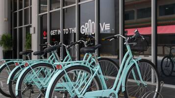 Una fila de bicicletas turquesas estacionadas frente a un edificio con grandes ventanales y un cartel que dice 'Get in to the Grio'.