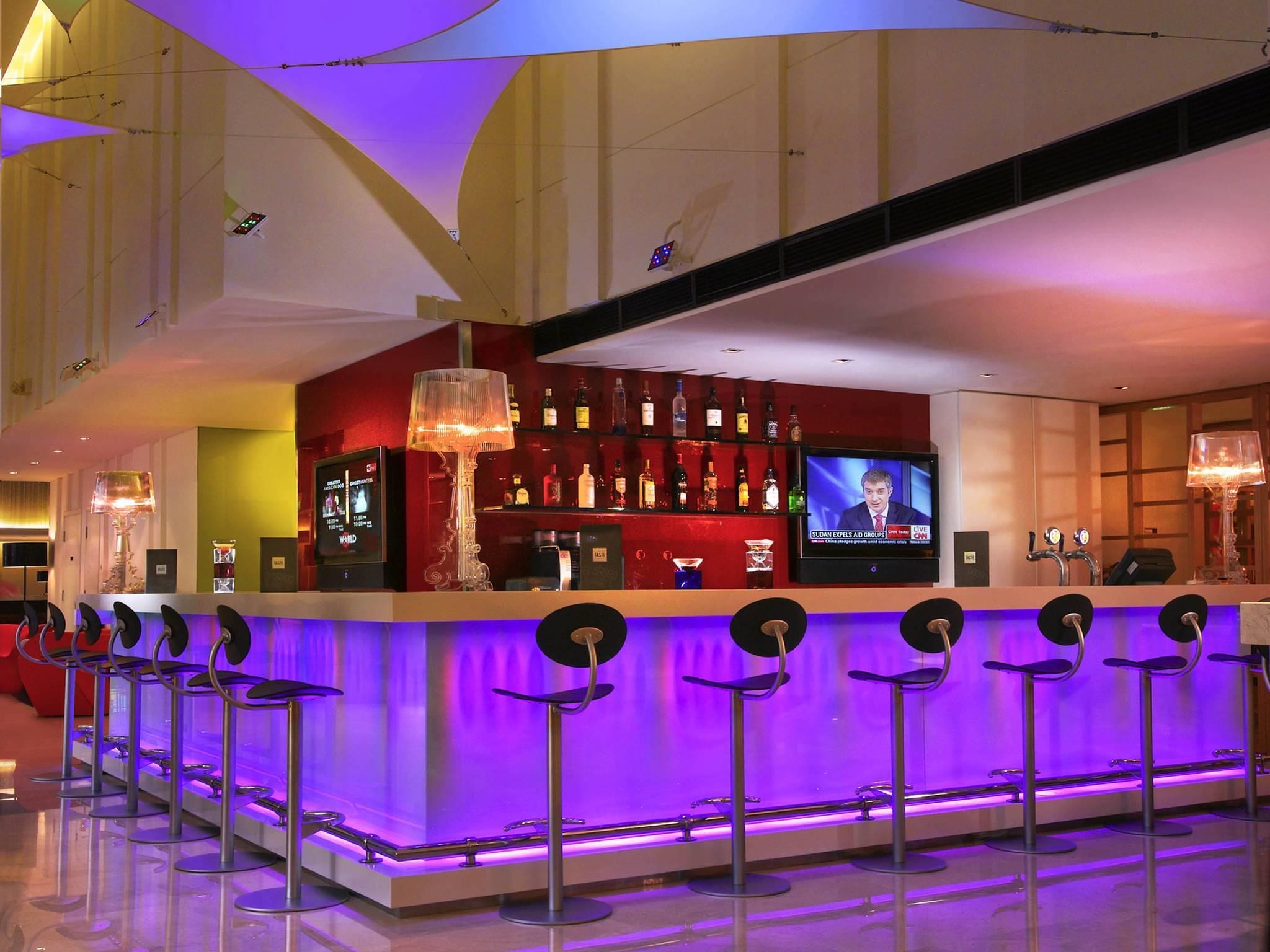 Eine Bar mit Fernseher, mehreren Barhocker und einer Theke.