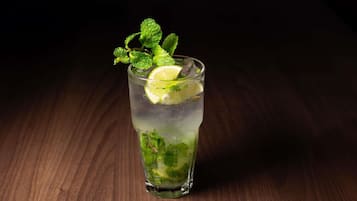 A glass of a clear beverage with lime and mint garnish on a wooden surface.