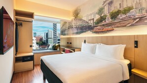 Habitación de hotel con cama, escritorio, armario y ventana grande con vista panorámica a la ciudad.