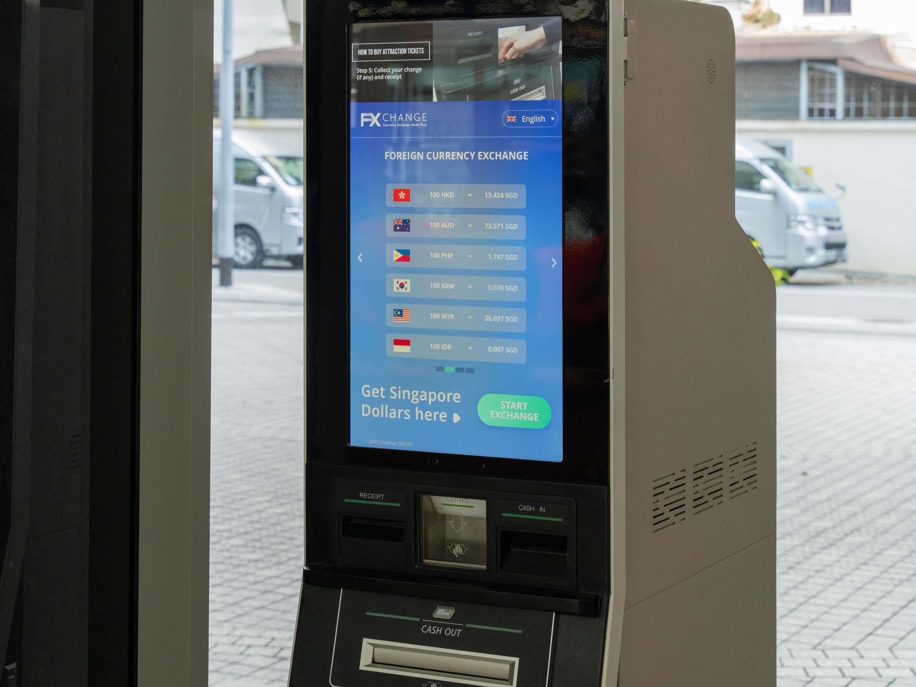 A currency exchange machine with a digital display showing foreign currency exchange rates.