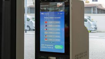 A currency exchange machine with a digital display showing foreign currency exchange rates.