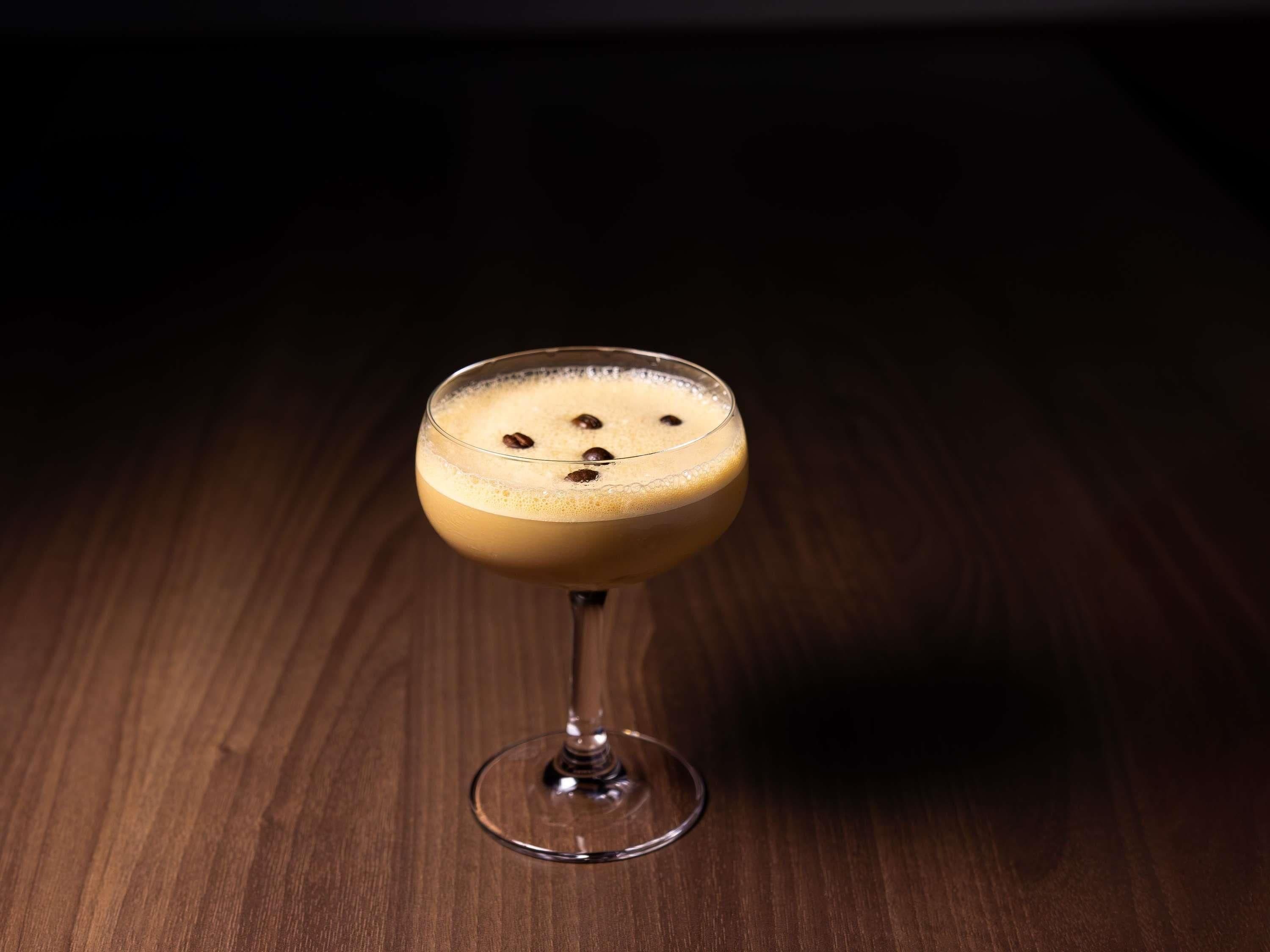 Et glas med et lagdelt drikkemiddel på en træoverflade.