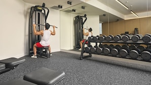 Une salle de sport équipée de matériel d’exercice, d’un miroir et d’un porte-haltères.