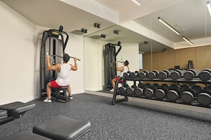 A gym with exercise equipment, a mirror, and a rack of dumbbells.
