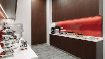Una cocina moderna con encimera blanca, electrodomésticos de acero inoxidable y una vitrina iluminada con luz roja.