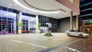 Un edificio moderno con amplios ventanales, una entrada curva y un letrero que indica 'Singapore'.