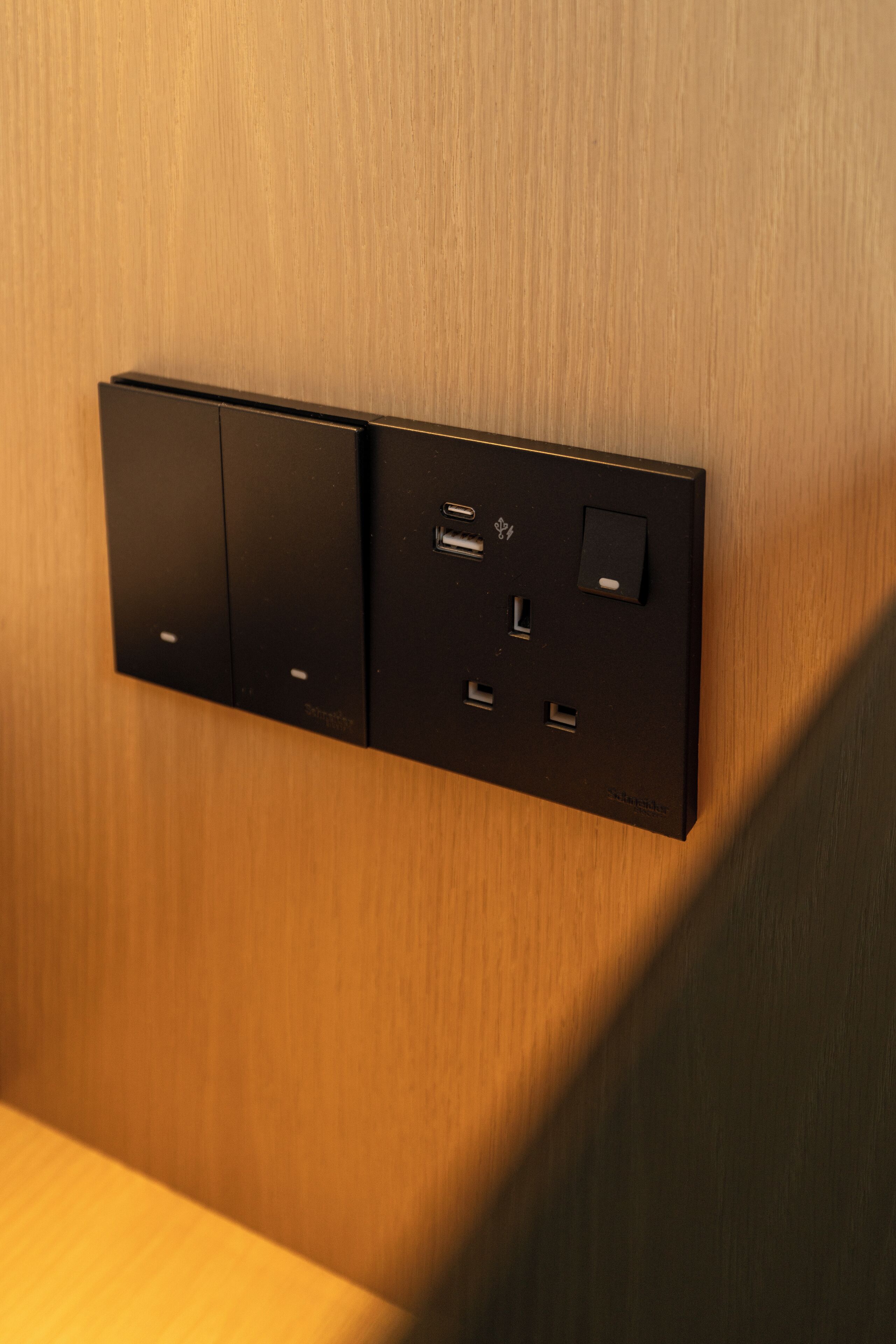 Un cuadro eléctrico con varios enchufes e interruptor, sobre un panel de madera.