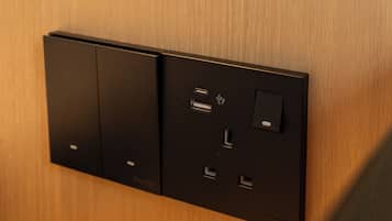 A wall-mounted electrical panel with multiple sockets and a switch, set against a wooden wall.
