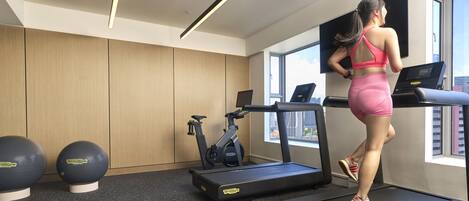 A modern gym with treadmills, stationary bikes, and exercise balls.