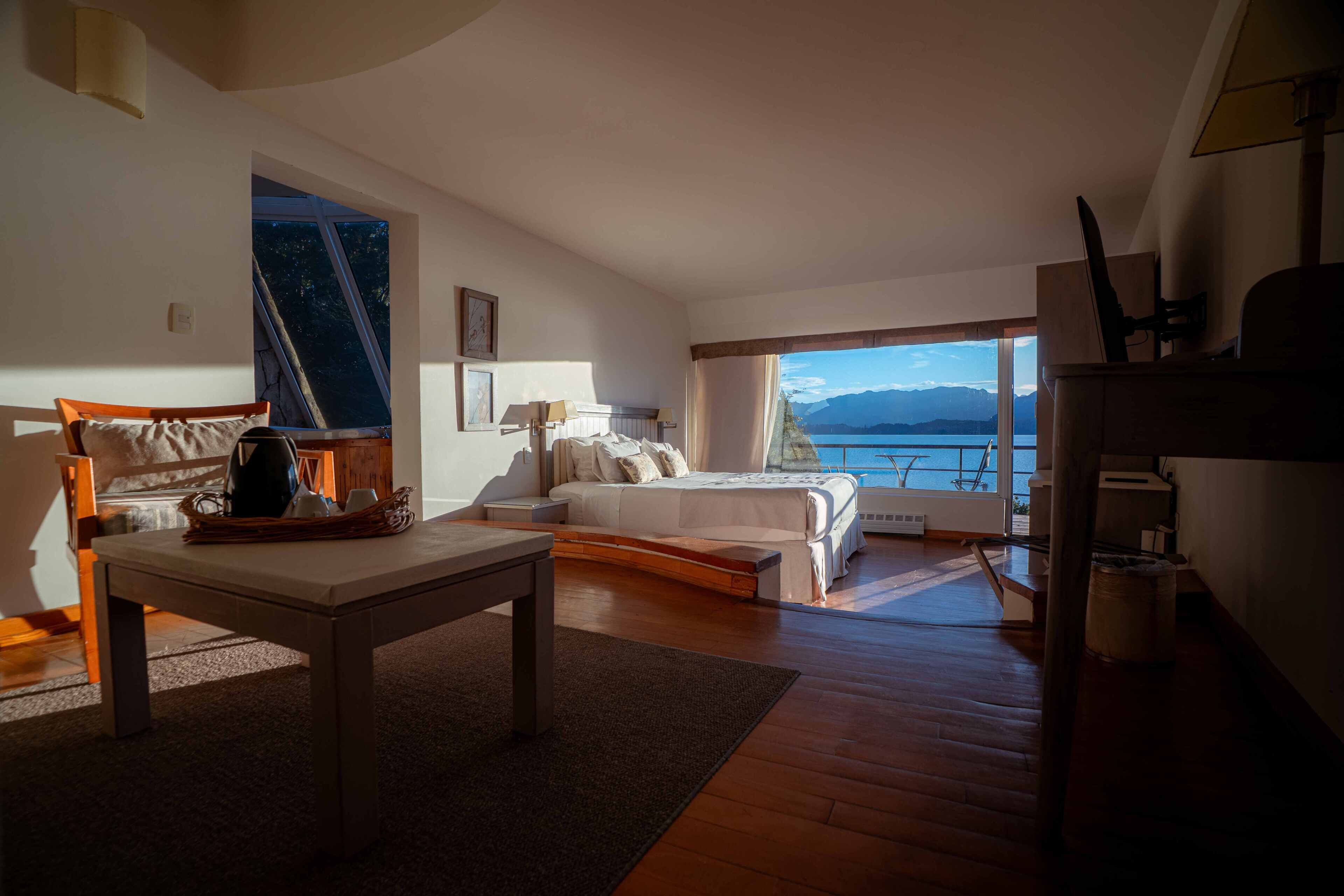 Un dormitorio con cama, una mesa, una silla y vista al mar.
