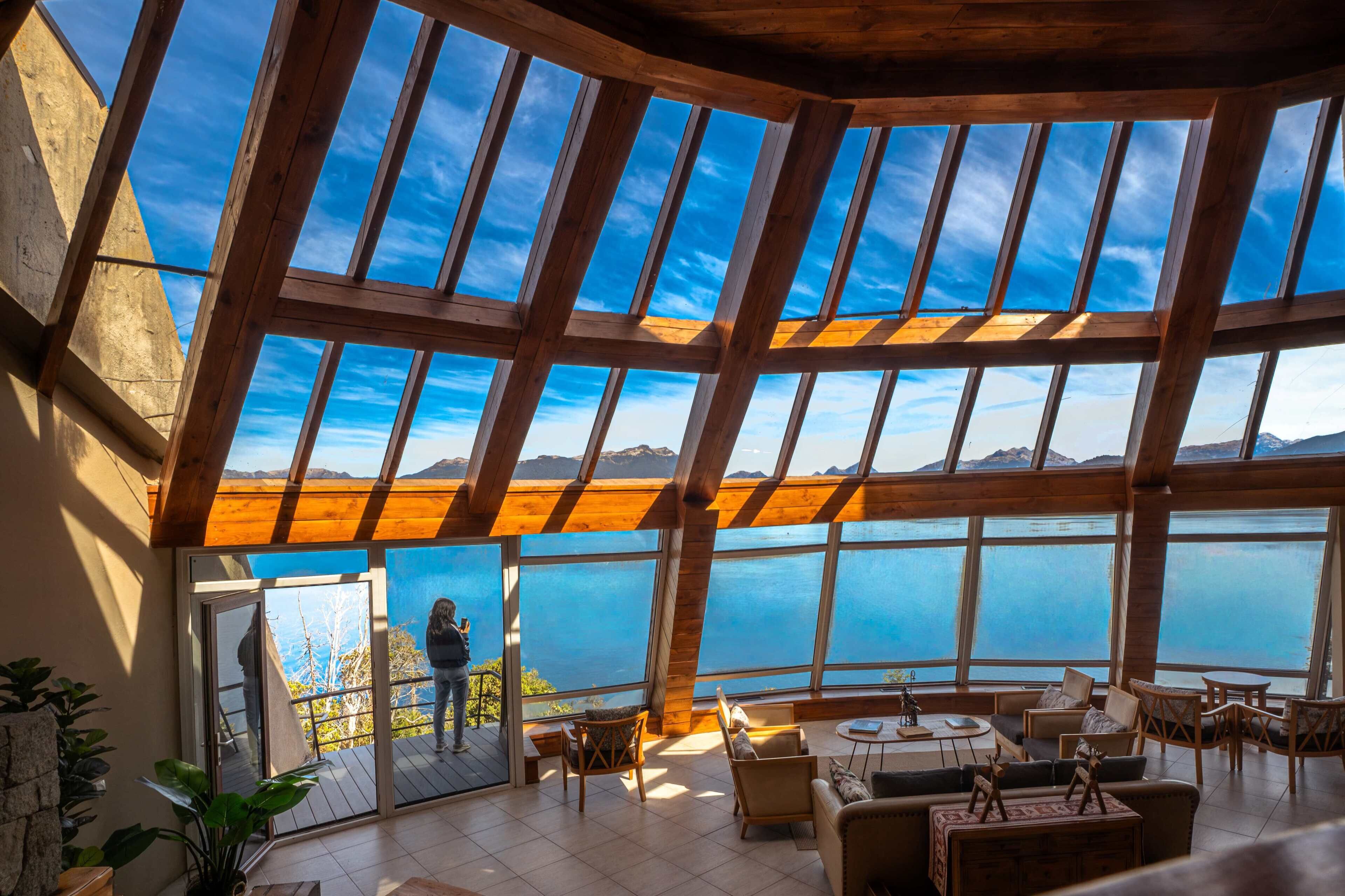 A spacious interior with a high ceiling and large windows offering a view of the sea and mountains.