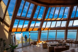 Un interior espacioso con techo alto y ventanas amplias que ofrecen vistas al mar y a las montañas.