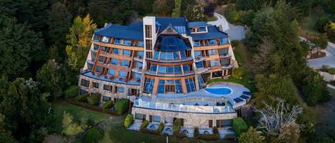 A multi-story building with a curved roof, a swimming pool, and a well-maintained garden.