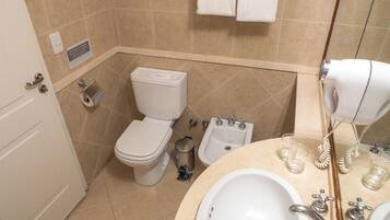 A bathroom with a toilet, bidet, sink, and a towel rack.