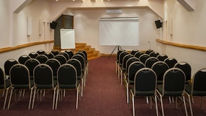 A conference room with rows of chairs, a whiteboard, and a projector screen. - Sol Arrayan Hotel & Spa (Villa La Angostura)