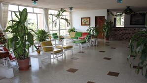Un vestíbulo amplio con varias zonas de estar, ventanas grandes y plantas en macetas.