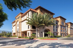 Un hotel de varios pisos con fachada color beige, un letrero llamativo de 'Four Points' y una palmera en primer plano.