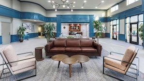 A spacious lobby with a brown leather sofa, two armchairs, and three round tables. - Four Points by Sheraton Ontario-Rancho Cucamonga (Rancho Cucamonga)