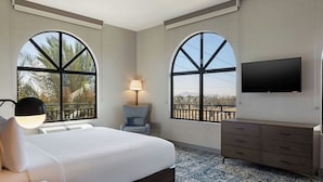 A bedroom with a large bed, a TV mounted on the wall, and two large windows with a view of palm trees. - Four Points by Sheraton Ontario-Rancho Cucamonga (Rancho Cucamonga)