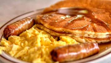 En tallrik med pannkakor, korv och äggröra.