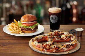 A burger, fries, a pizza, and a glass of beer on a wooden table. - Four Points by Sheraton Ontario-Rancho Cucamonga (Rancho Cucamonga)