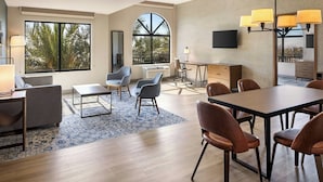 A modern hotel room with a large window, a dining area, a desk, and a TV. - Four Points by Sheraton Ontario-Rancho Cucamonga (Rancho Cucamonga)