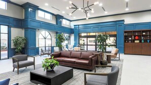 A spacious lobby with a brown leather sofa, grey armchairs, and a coffee table with a plant. - Four Points by Sheraton Ontario-Rancho Cucamonga (Rancho Cucamonga)