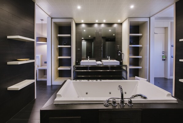 Un baño moderno con una bañera grande, dos lavamanos y un espejo amplio.