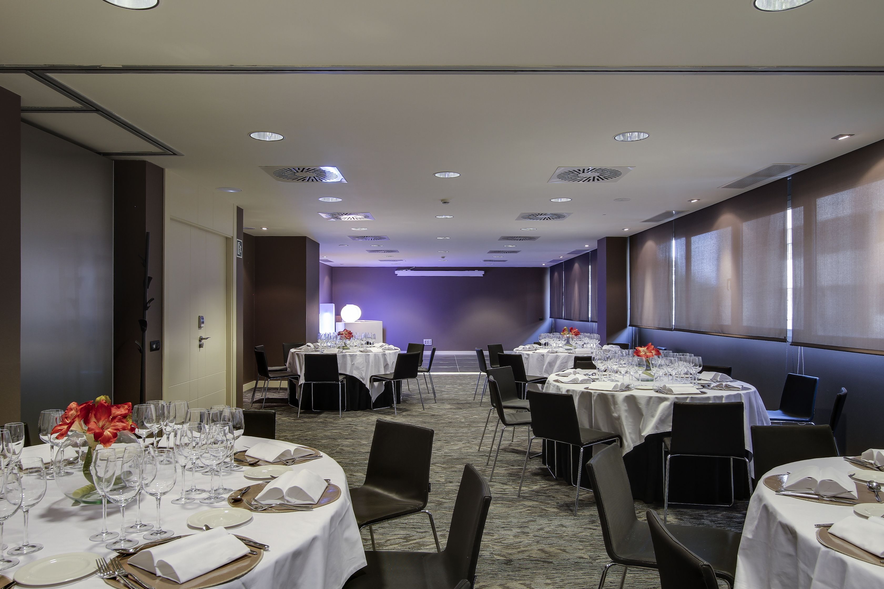 Un salón de conferencias con mesas redondas, sillas y una zona de escenario.