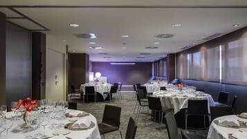 Un salón de conferencias con mesas redondas, sillas y una zona de escenario.
