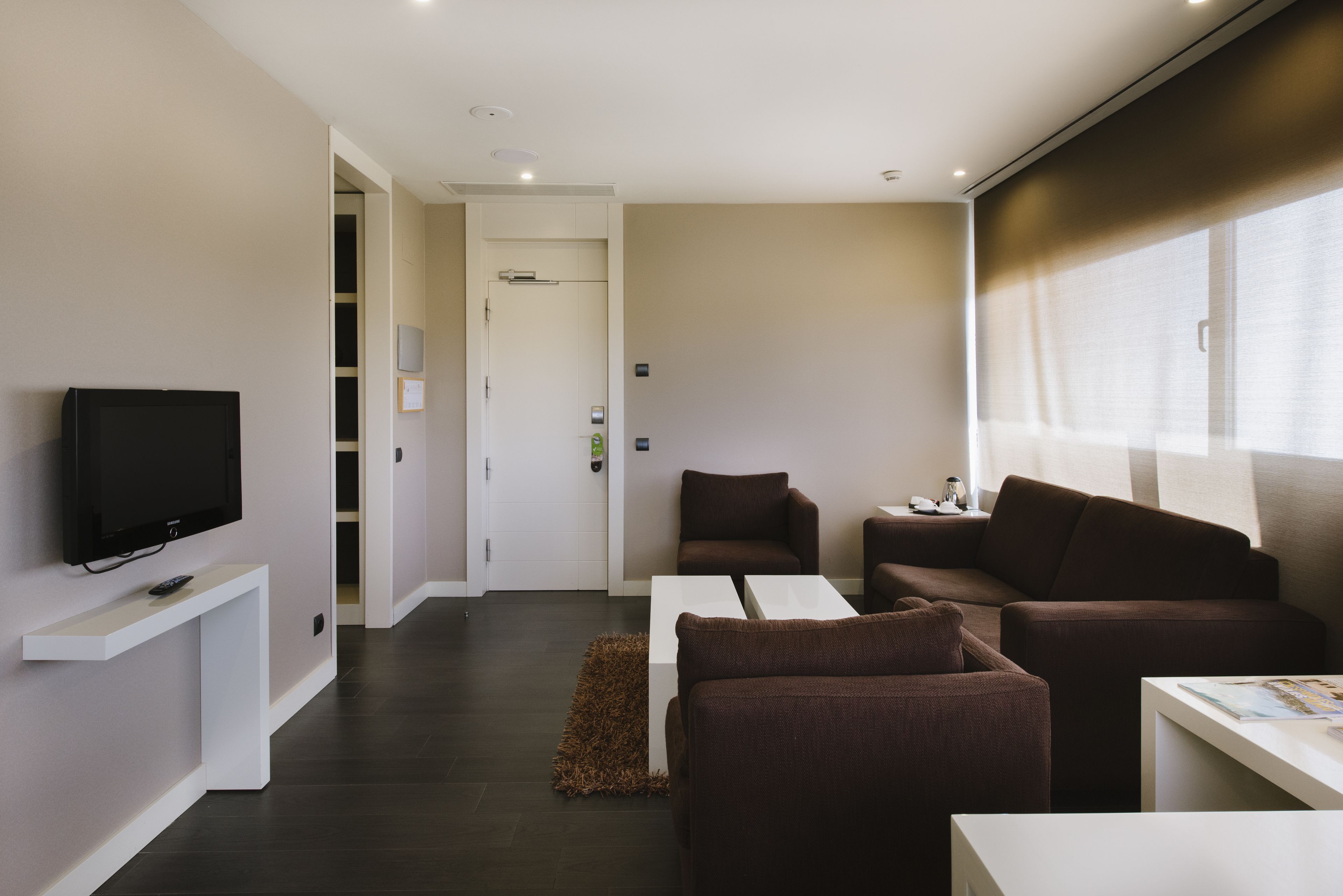 Un salon moderne avec un téléviseur à écran plat, un canapé, une table basse et une petite table avec une lampe.