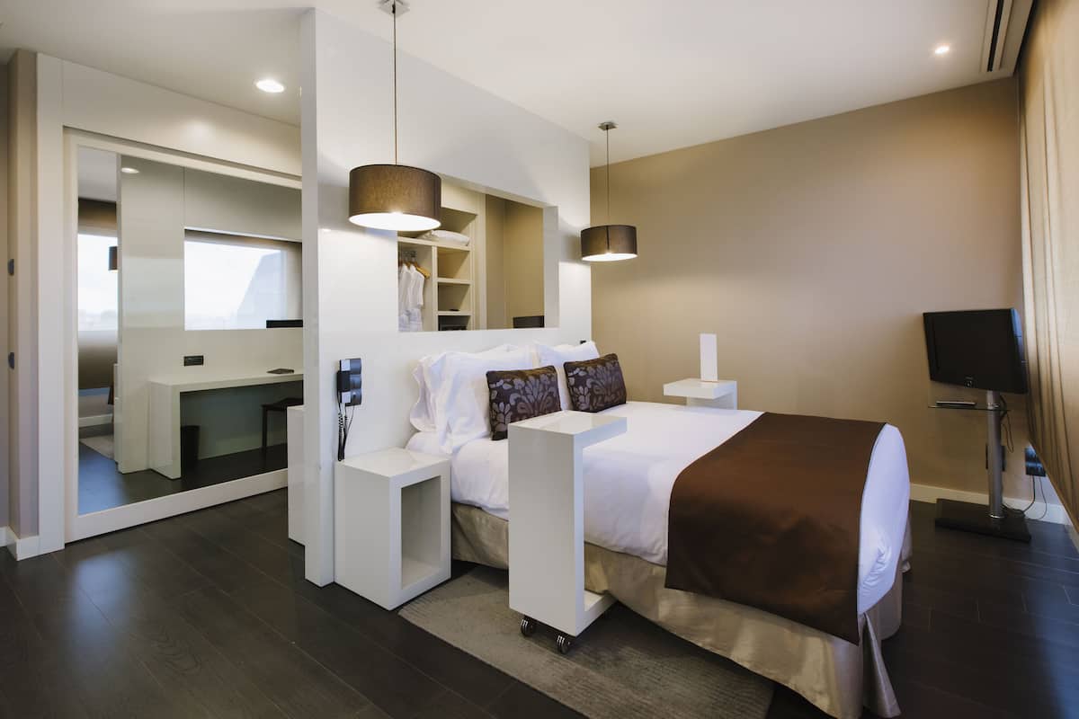 A modern hotel room with a large bed, a desk, and a walk-in closet.