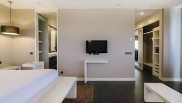Una habitación de hotel moderna con una cama grande, un televisor en la pared y un vestidor.