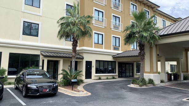 A multi-story hotel with a beige facade, balconies, and palm trees. - Comfort Inn & Suites Fort Walton Beach - Destin West (Fort Walton Beach)