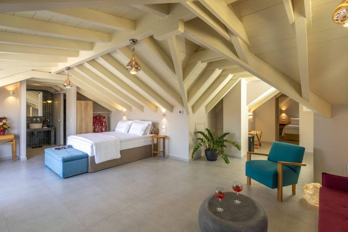 Un ampli dormitori tipus loft amb un llit gran, un butac armchair blau i un sofà vermell.