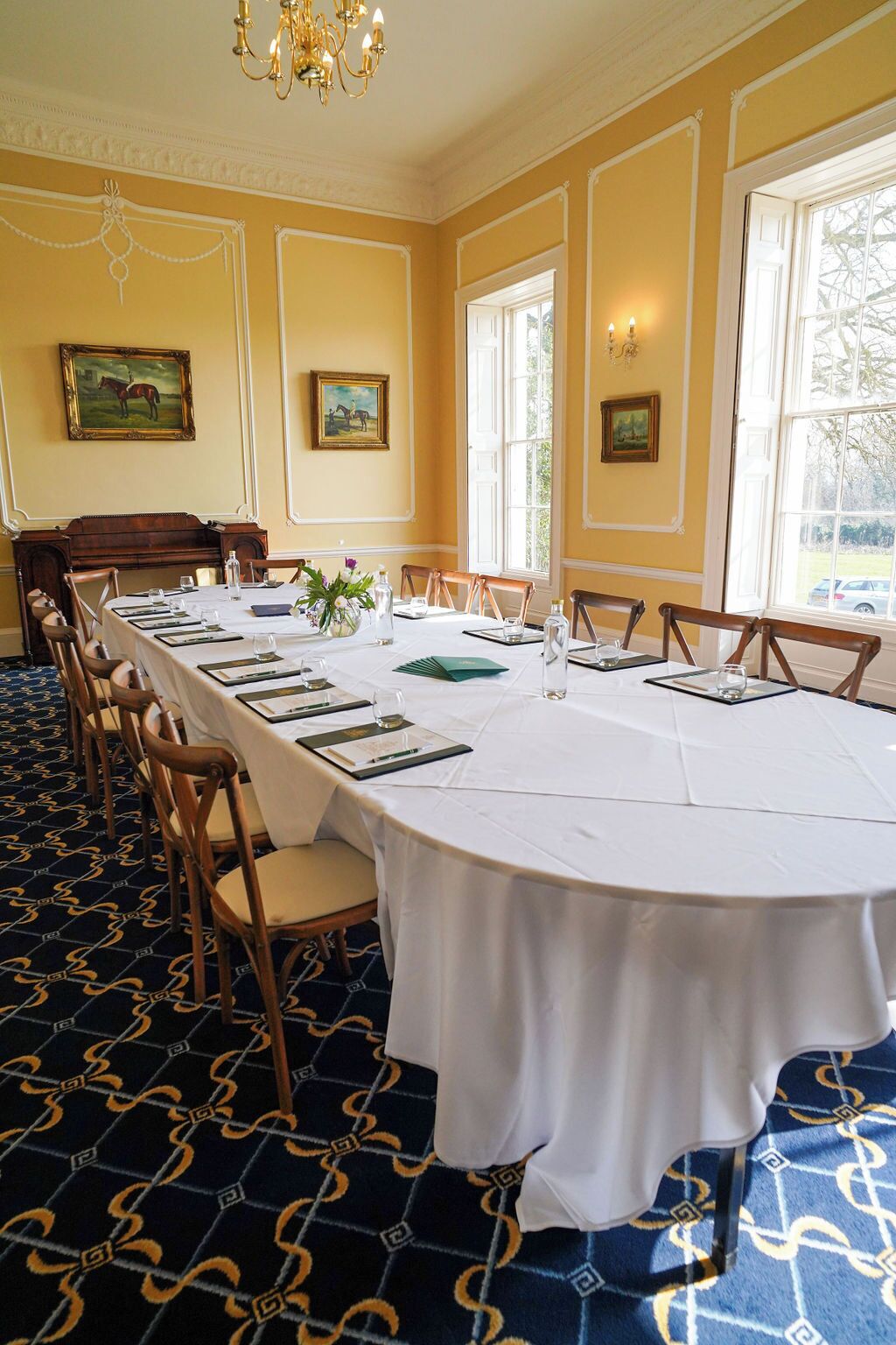 A formal dining room with a long table set for a meal, surrounded by chairs.
