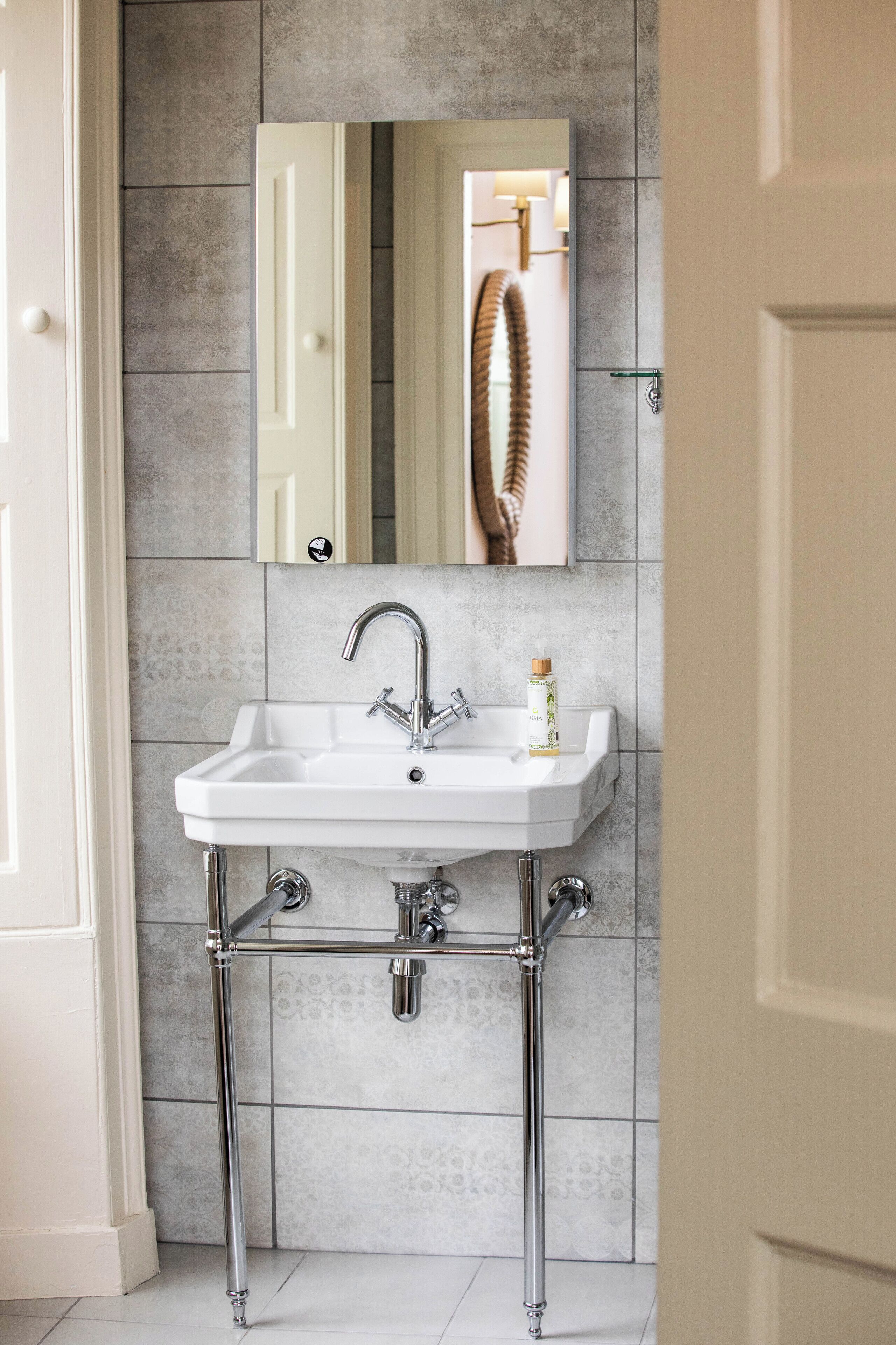 A bathroom with a white sink, chrome faucet, and a mirror above it.