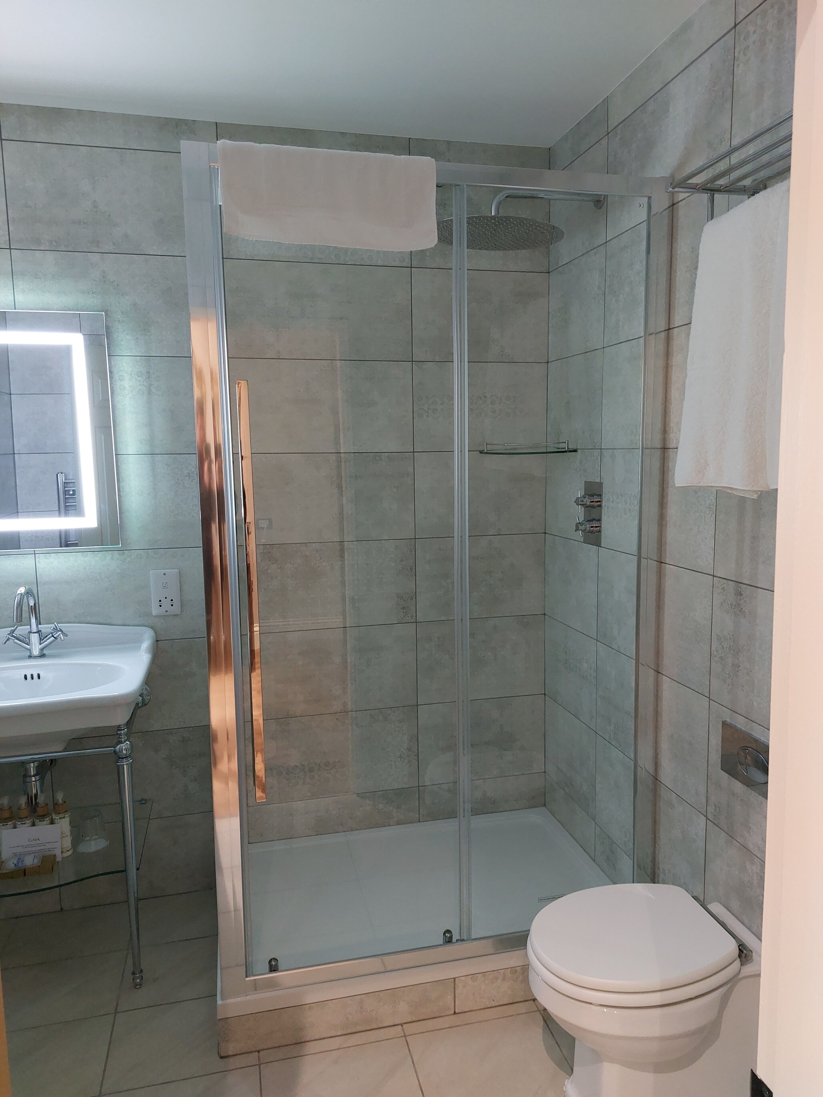 Une salle de bain avec une douche à parois de verre, un lavabo blanc et des toilettes.