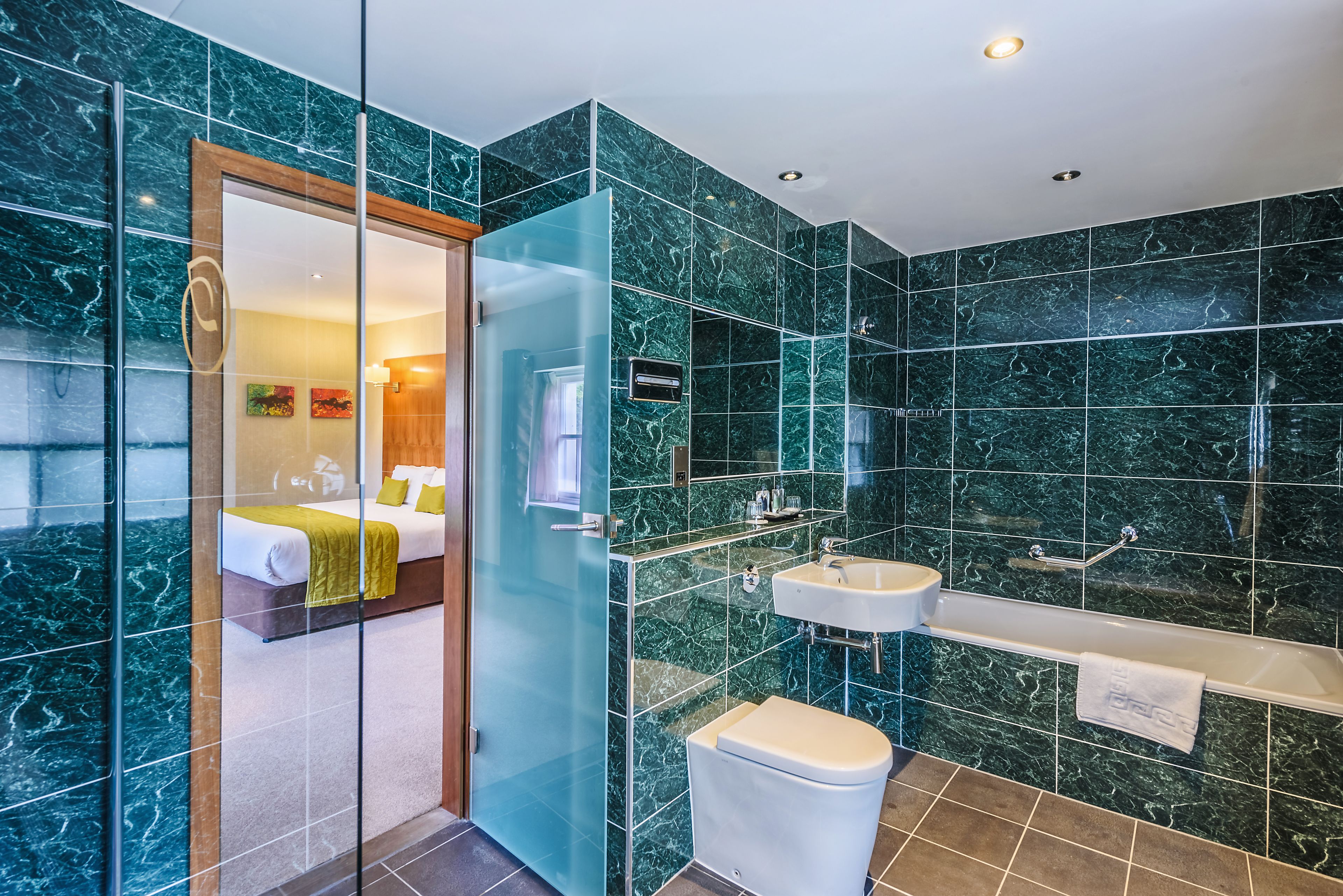 A modern bathroom with a glass shower enclosure, a white toilet, and a vanity with a sink and mirror.