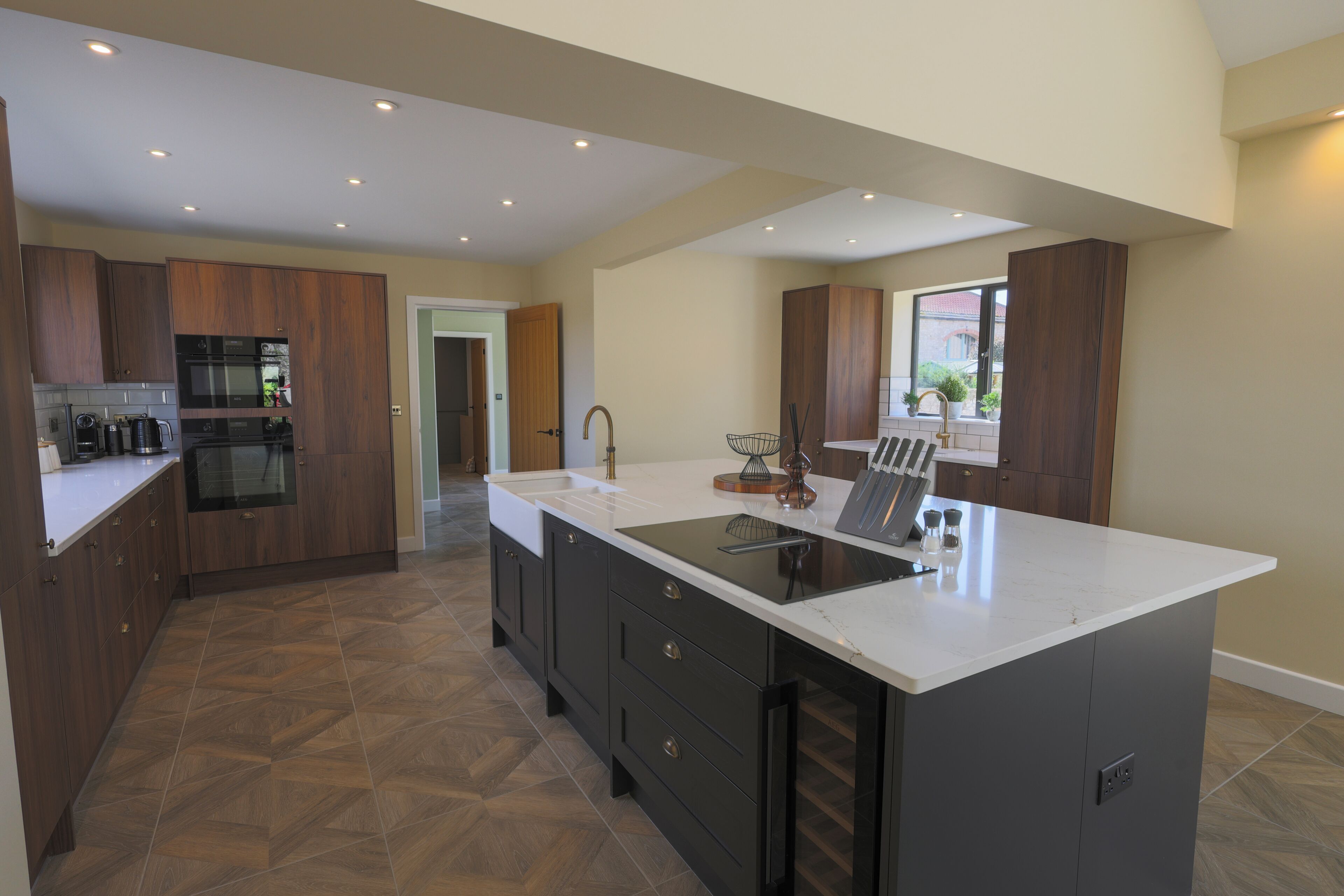 A modern kitchen with dark cabinetry, a white countertop, and a large island with a sink.