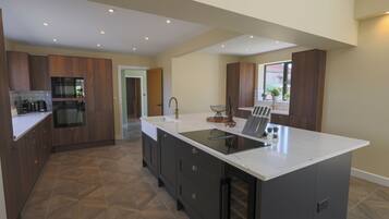 A modern kitchen with dark cabinetry, a white countertop, and a large island with a sink.