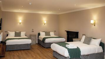A hotel room with two beds, wooden flooring, and wall-mounted lighting.