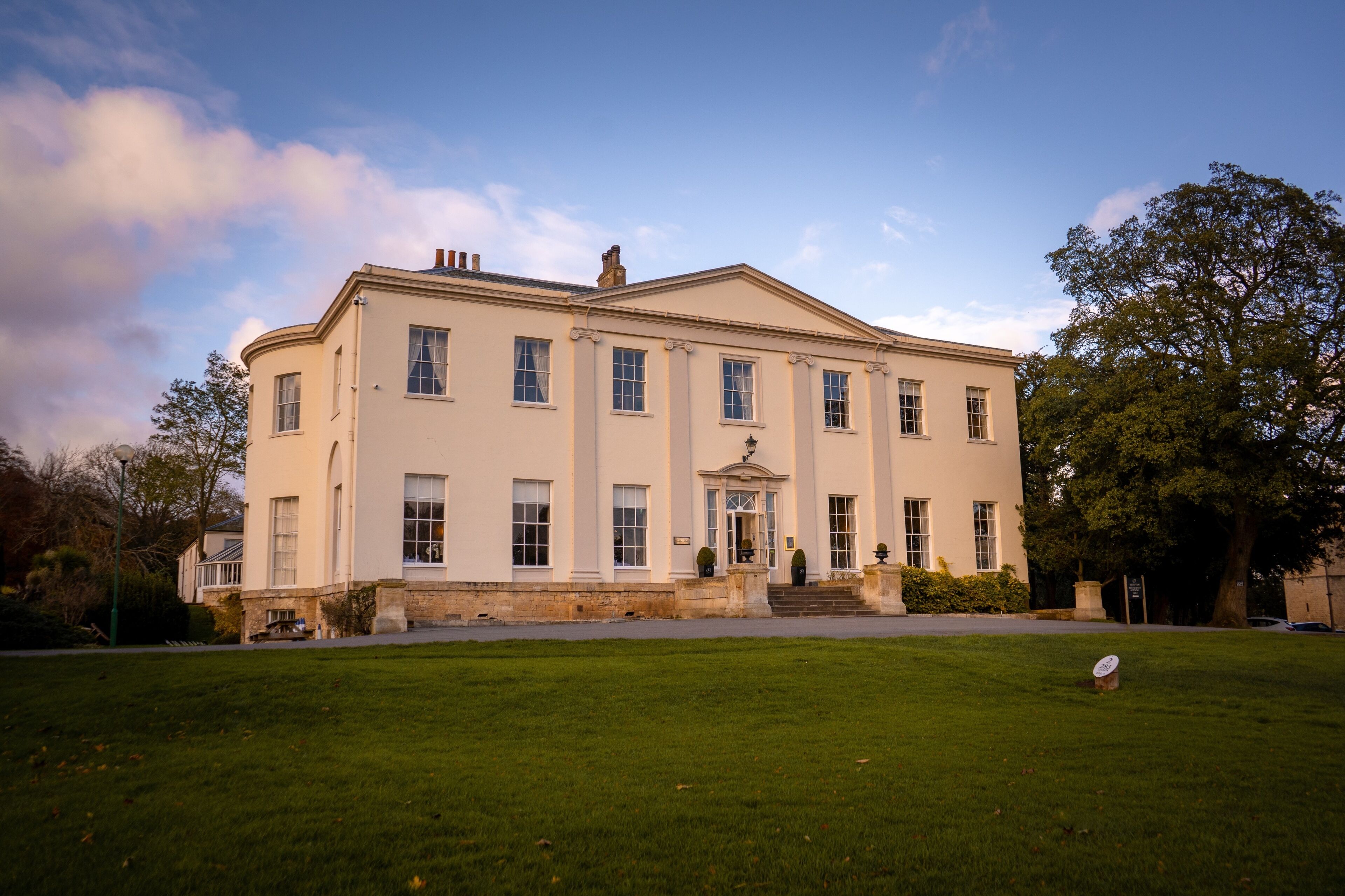 A large, two-story building with a symmetrical facade, a central entrance with steps, and a well-maintained lawn in the foreground.