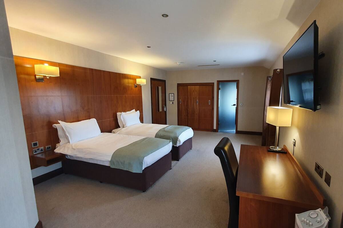 A hotel room with two beds, a desk, a TV, and a wardrobe.