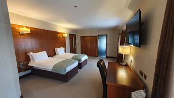 A hotel room with two beds, a desk, a TV, and a wardrobe.