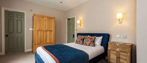 A bedroom with a bed, wooden wardrobe, and wall-mounted light fixtures.
