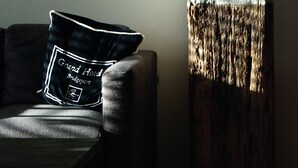 A sofa with a pillow and a wooden vase. - Hotel Koogerend (Den Burg)